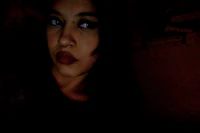 a girl in a dark room looking into the camera