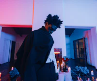 a man in a black cape standing in front of candles