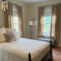 a bedroom with two windows and a bed