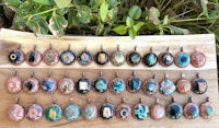 a group of pendants with different colored stones on a wooden board