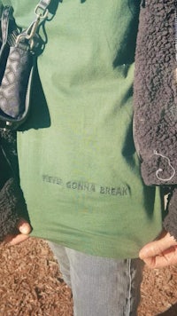 a person holding a green t - shirt that says i'm gonna break
