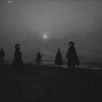a black and white photo of a group of people walking on the beach