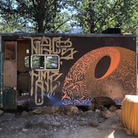 a food truck in the woods with graffiti on it