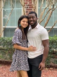 a man and woman posing for a picture in front of a house