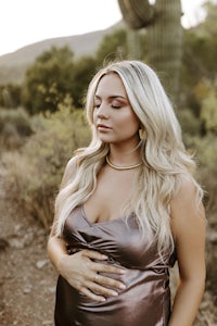 a pregnant woman in a metallic dress in front of a cactus