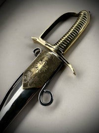 a sword with a gold handle on a white surface