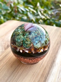 a small glass sphere filled with green and brown rocks