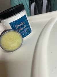 a jar of body butter sitting on a white plate