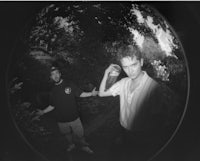 a black and white photograph of two men in the woods