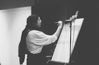 black and white photo of a woman painting on an easel