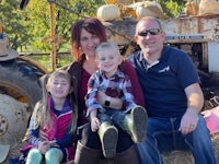 a family sits in front of a tractor and pumpkins