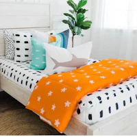 a bed with orange and white bedding and pillows