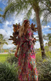 a woman wearing a colorful kaftan in front of palm trees