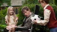 a man in a wheelchair with two children playing with a soccer ball