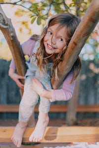 a little girl sitting on a tree branch