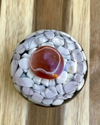 a small box with a red stone and white pebbles