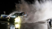 a car driving through a puddle of water at night