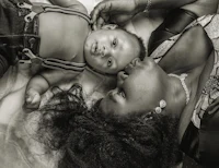 a black and white photo of a woman laying on a bed with a baby