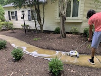 a man cleaning a sidewalk in front of a house