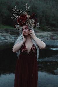 a woman in a burgundy dress standing by a river