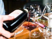 a person pouring wine into glasses on a table