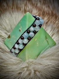 a bracelet with blue and green beads on top of a fur rug