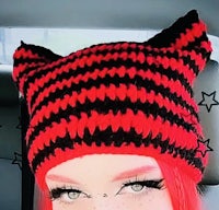 a woman wearing a black and red knitted cat hat