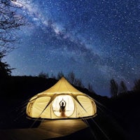 a person is sitting in a yurt under the stars