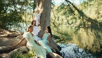 a group of women sitting on a tree near a lake
