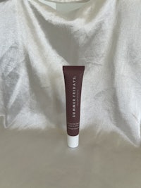 a tube of face cream sitting on a white cloth