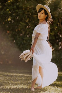 a woman wearing a white dress and hat in the grass