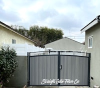 a driveway with a black gate in front of it