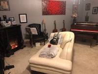 a living room with a piano, guitars, and a fireplace