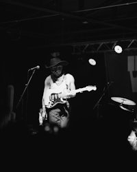 a black and white photo of a man playing guitar on stage