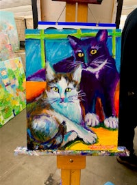 a painting of two cats on a easel