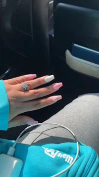 a woman sitting in a car with pink and blue nails