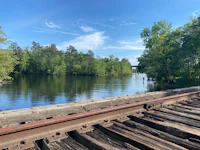 a railroad bridge over a river with trees in the background
