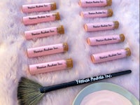 a group of pink lipsticks and a brush on a pink fur rug