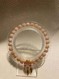 a pink stone beaded bracelet on a clear glass holder