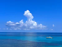 a boat is floating in the blue water near a cloudy sky