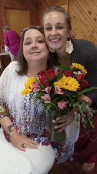two women posing for a photo with flowers