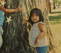 a girl is standing next to a tree