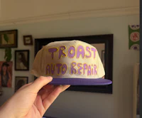 a person is holding up a hat that says toast auto repair