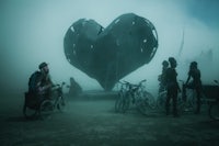 a group of people standing in front of a heart shaped sculpture