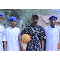 four young men standing next to each other holding basketballs