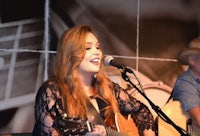 a woman singing and playing an acoustic guitar