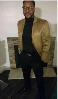 a man wearing a tan blazer and black pants
