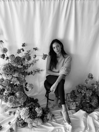 a black and white photo of a woman posing in front of flowers