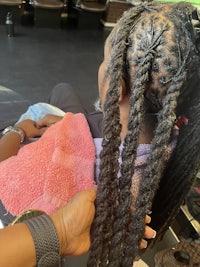 a woman getting her hair braided in a salon