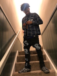 a man wearing a plaid shirt standing on stairs
